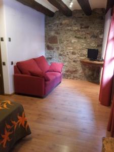 a red couch in a room with a stone wall at Casa Rafeleta Hotel in Plan