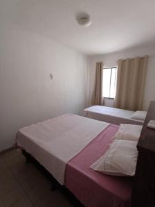 a hotel room with two beds and a window at Apartamento no Condomínio Jardim Vitória, Juazeiro-BA in Juazeiro