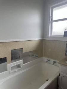 a white bath tub in a bathroom with a window at 3 bedrooms House,77 Slacks Rd in Palmerston North