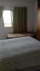 ein Schlafzimmer mit einem Bett und einem Fenster in der Unterkunft Apartamento in Itanhaém
