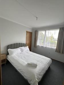 a bedroom with a white bed with a window at 3 bedrooms House,77 Slacks Rd in Palmerston North