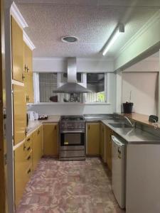 a kitchen with yellow cabinets and a stove top oven at 3 bedrooms House,77 Slacks Rd in Palmerston North +5 photos