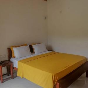 Un dormitorio con una cama con una manta amarilla encima. en Forest & Fields Retreat by Sinharaja, en Deniyaya