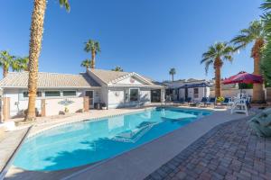 a swimming pool in front of a house with palm trees at The Perfect Getaway & Bunkhouse Casita with Heated Pool & Epic Game Room in Mesquite