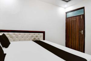 - une chambre avec un lit et une porte en bois dans l'établissement Collection O Gorakhpur Industrial Area Shaurya Inn, à Pipra