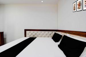 - une chambre avec un lit blanc et des oreillers noirs dans l'établissement Collection O Gorakhpur Industrial Area Shaurya Inn, à Pipra