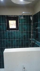 a bathroom with a green tiled wall with a window at Aynabend - cabin house for rent in Sheki in Sheki