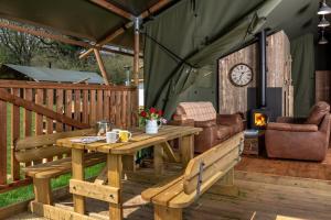 TalybontにあるBwncath Glamping Lodgeのテーブルと椅子と時計のあるパティオ
