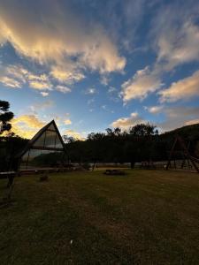 a large triangular building in a field with a cloudy sky at Cabana Pehuen in Santa Maria do Erval