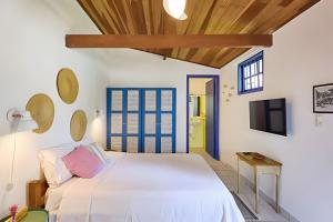 a bedroom with a white bed and a tv at Chalé no Itaguá, ao lado do aquário de Ubatuba in Ubatuba
