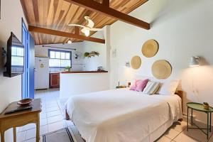 a bedroom with a large white bed and a kitchen at Chalé no Itaguá, ao lado do aquário de Ubatuba in Ubatuba