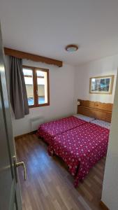 a bedroom with a bed with a red comforter at Appartement 4 pièces pour 6-8 personnes, 3 chambres, 2 canapés-lit double dans le salon, au pied des pistes et piscine l'été, wifi fibre in Arvieux