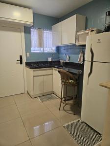 een keuken met een witte koelkast en een spoelbak bij Loft encantador próximo a Roda Gigante,excelente localização com ar condicionado in Balneário Camboriú +11 foto's