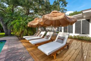 a group of chairs and umbrellas on a wooden deck at 9BR Heated Pool Hot Tub Sleeps 25 in Largo