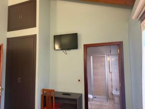 a bathroom with a toilet and a television on the wall at Hotel Rural Las Palmeras Muskiz in Muskiz