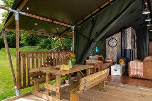 a green tent with a wooden table and bench at Hebog Glamping Lodge in Talybont