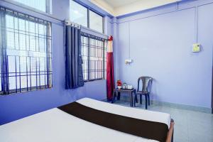 a bedroom with blue walls and a bed and a chair at Hotel O Dream Lodge in Nowgong