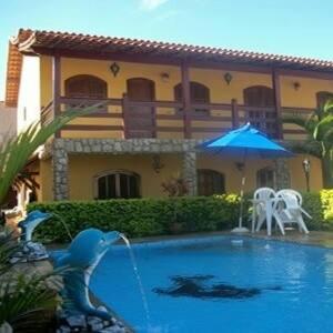 a swimming pool with a bird in front of a house at Pousada Da Restinga in Cabo Frio