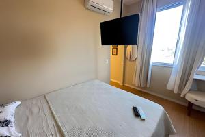 a bedroom with a bed with a tv and remote controls at Mario401| Loft in Leblon next do Lagoa in Rio de Janeiro