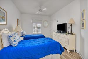 two blue beds in a white room with a tv at St. Simons Grand #305 in Saint Simons Island +33 photos