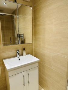 een badkamer met een witte wastafel en een spiegel bij Westferry Deluxe Apartment 3 in Londen +8 foto's