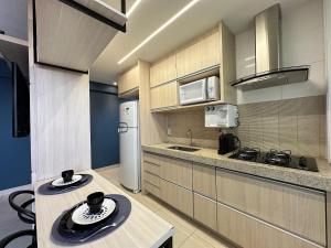 a kitchen with wooden cabinets and a white refrigerator at iFlat Lozandes Flamboyant Jardim Goiás in Goiânia