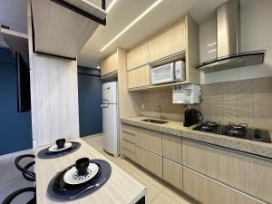 a kitchen with wooden cabinets and a white refrigerator at iFlat Lozandes Flamboyant Jardim Goiás in Goiânia