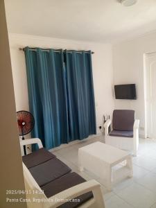 ein Wohnzimmer mit blauen Vorhängen und einem Stuhl in der Unterkunft Hogar cerca de la playa in Punta Cana