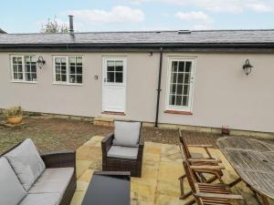 a white house with a patio and chairs at Rose Stables in Bampton