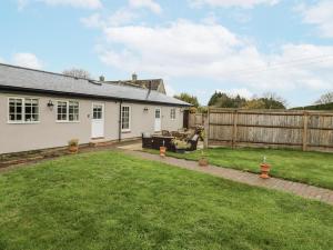 a garden with a white house and a fence at Rose Stables in Carterton