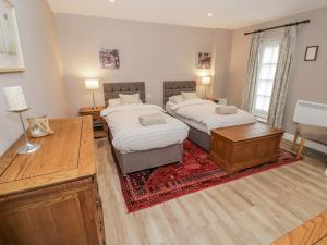 a bedroom with two beds and a table and a desk at Rose Stables in Carterton