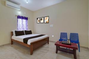 a bedroom with a bed and a table in it at Hotel O Kalpatharu Boarding and Lodging in Tyāmagondal +23 photos