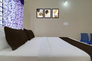 a bedroom with a bed with three pictures on the wall at Hotel O Kalpatharu Boarding and Lodging in Tyāmagondal