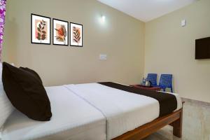 a bedroom with a white bed with three pictures on the wall at Hotel O Kalpatharu Boarding and Lodging in Tyāmagondal