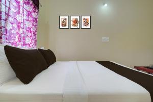 a bedroom with a white bed with three pictures on the wall at Hotel O Kalpatharu Boarding and Lodging in Tyāmagondal