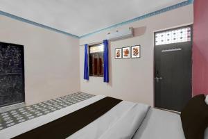 a bedroom with a bed and a door and a window at Hotel O Shubh Inn in Jhānsi