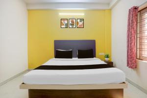 a bedroom with a large bed with yellow walls at HOTEL O AADRITI RESIDENCY in Bhubaneshwar