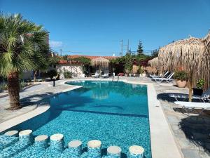 een zwembad in een resort met palmbomen en stoelen bij Secret Garden Hotel in Maleme