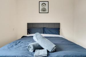 ein Bett mit einer blauen Decke und Handtüchern darauf in der Unterkunft Luxury 2-Bedroom Home 10 Minutes from Birmingham City Centre in Birmingham