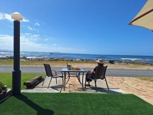 a person sitting at a table near the ocean at Tide's Edge in Gansbaai
