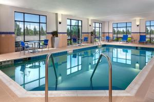 a pool in a hotel with blue chairs and tables at TownePlace Suites Buffalo Airport in Cheektowaga