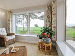 a living room with a large window and a couch at Garden Cottage in Petton