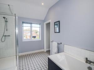 a white bathroom with a tub and a shower at Garden Cottage in Petton