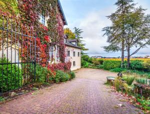 a house covered in ivy next to a brick driveway at Hôtel Le Clos des Arts in Gevrey-Chambertin