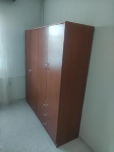 ein großer Holzschrank in der Ecke eines Zimmers in der Unterkunft PΑNSION Μελίκη 