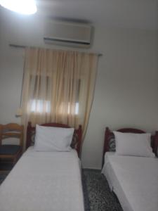 zwei Einzelbetten in einem Zimmer mit Fenster in der Unterkunft PΑNSION Μελίκη 