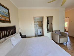 a bedroom with a large white bed and a chair at DuneSide Guesthouse in Richards Bay