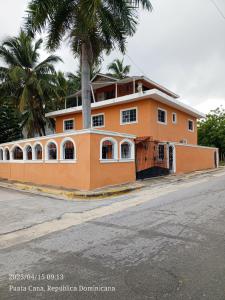 ein orangefarbenes Gebäude mit einer Palme vor einer Straße in der Unterkunft Hogar cerca de la playa in Punta Cana