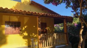 a small yellow house with a porch and a tree at Pousada Pássaros da Manhã in Vale do Capao