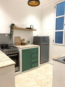 a kitchen with green cabinets and a stove top oven at Charming apartment heart of Medina 2 min Royal Palace Tetouan 2BR, Balcony in Tetouan